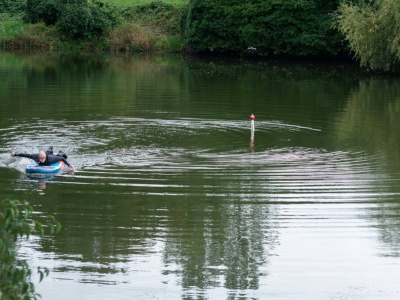 Mann auf Paddleboard paddelt im See bei einer Boje